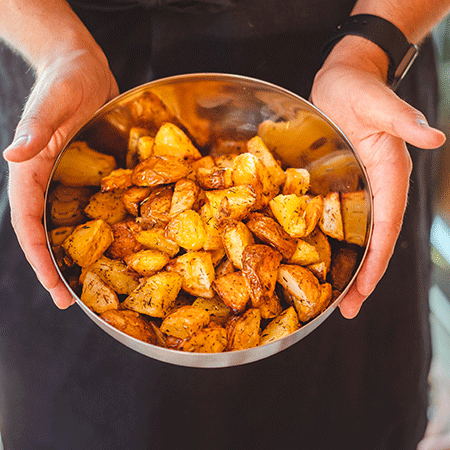 eine Person, die eine Schüssel mit Bratkartoffeln hält